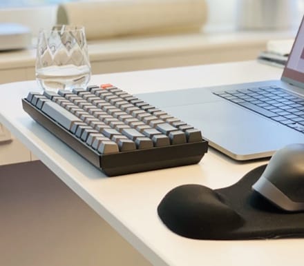 Typemaster keyboard placed on a desk, with a glass of water alongside.